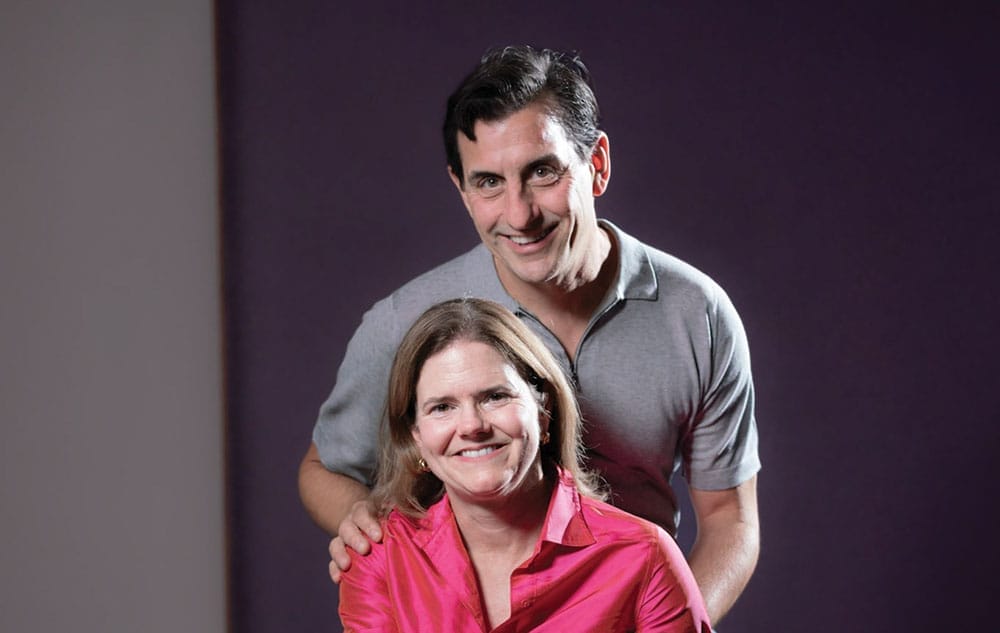 Man crouching behind a woman with his hand on her shoulder.