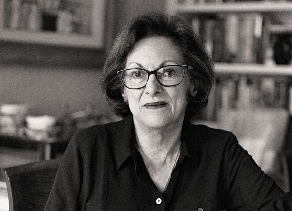 A black-and-white portrait of a woman wearing black-rimmed glasses and a dark-colored shirt.