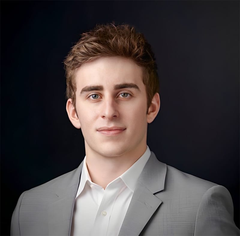 Headshot of a man in a gray suit jacket and white button-down shirt.