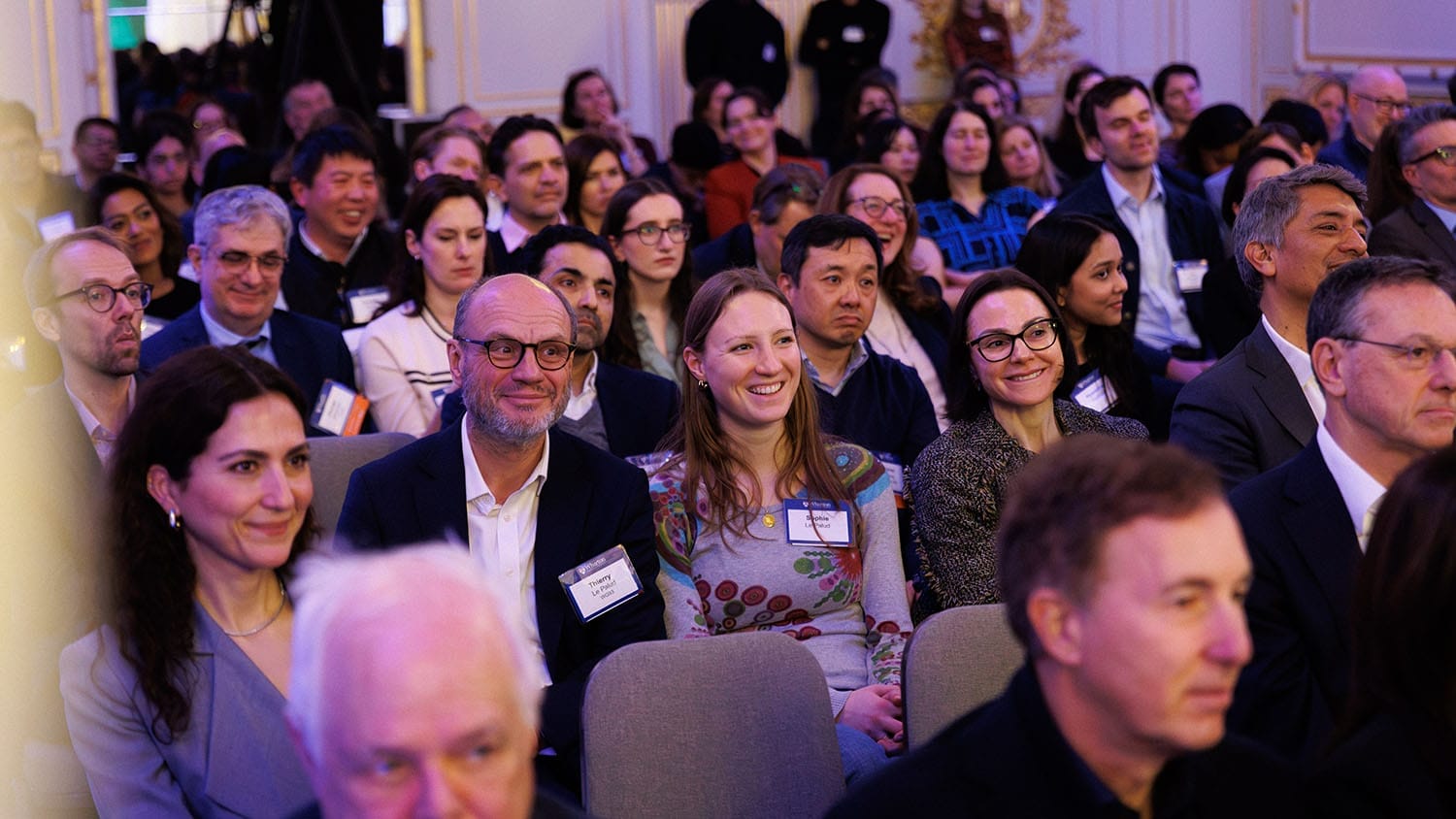 Smiling people seated in an audience.