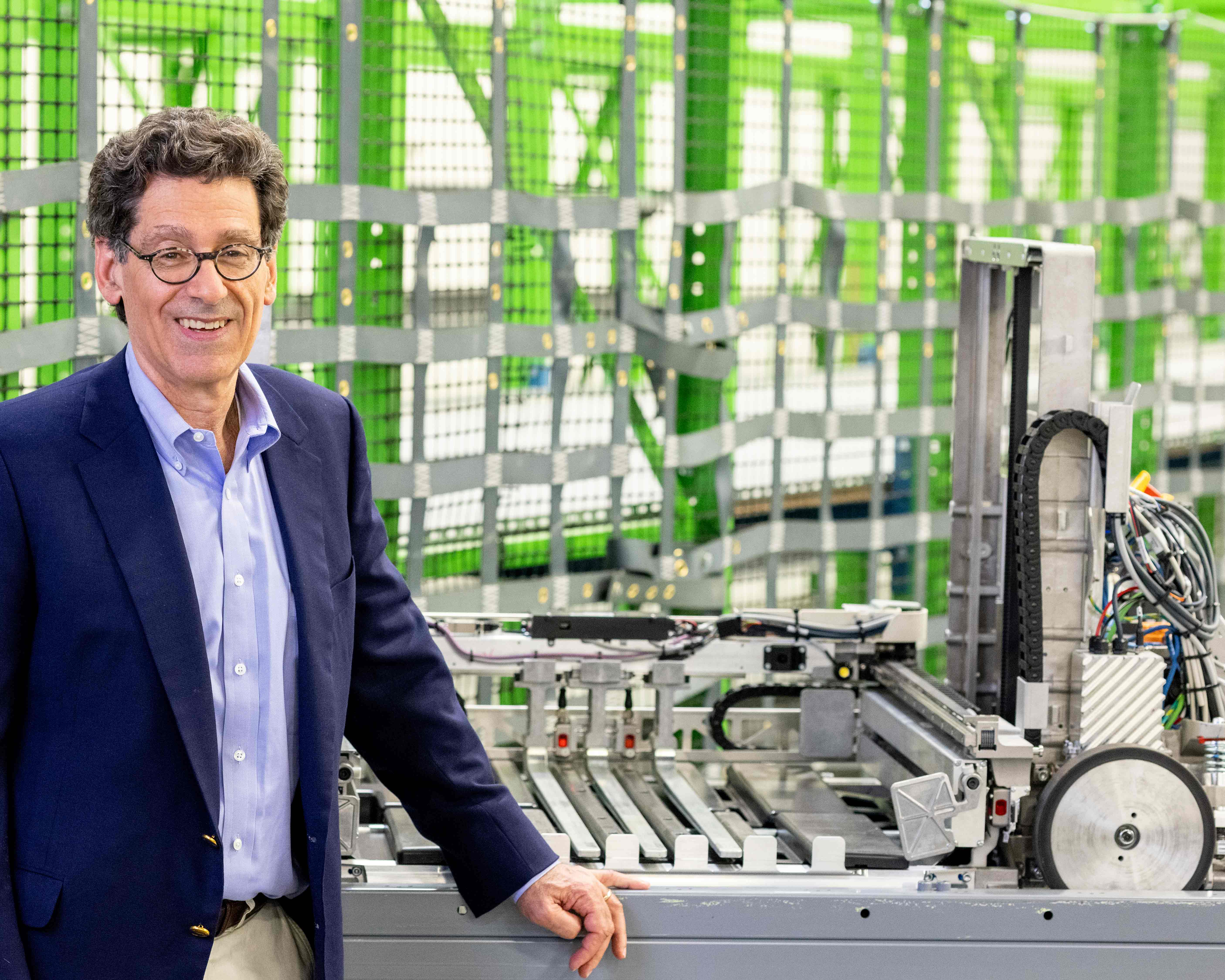 Man smiles and stands in front of robotic wheels and frame